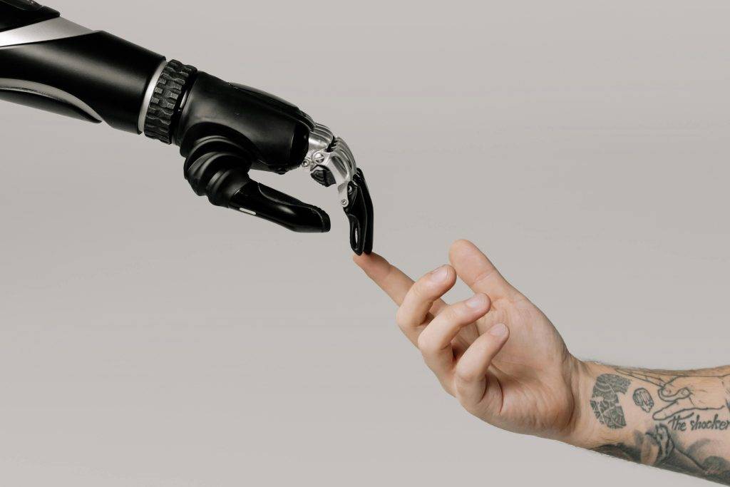A robot arm reaching out and touching the fingers of a human arm