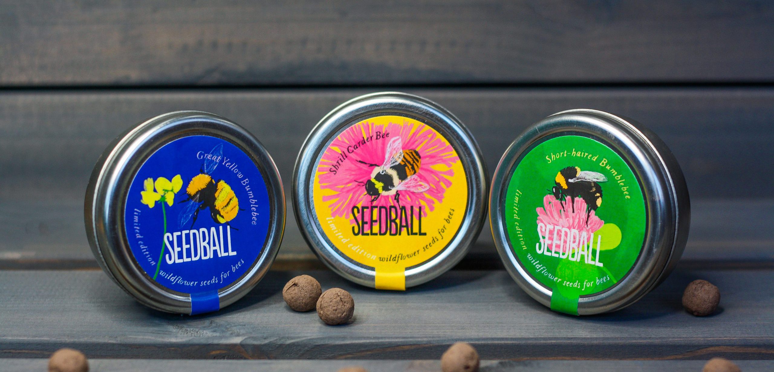 three metal tins in different colours with the branding 'Seedball' on