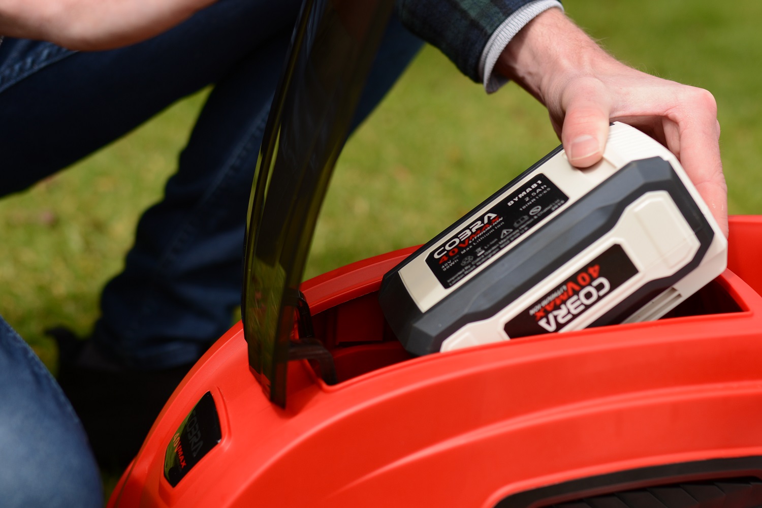 A man putting a battery pack into a red lawn mower