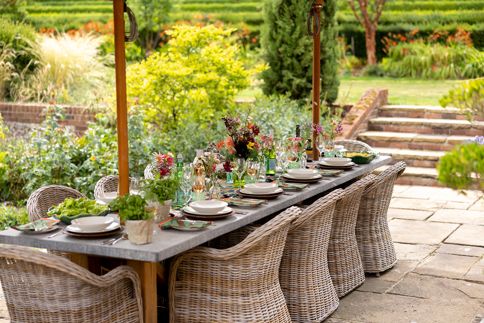 A decorated and laid garden table surrounded by woven chairs on a patio area