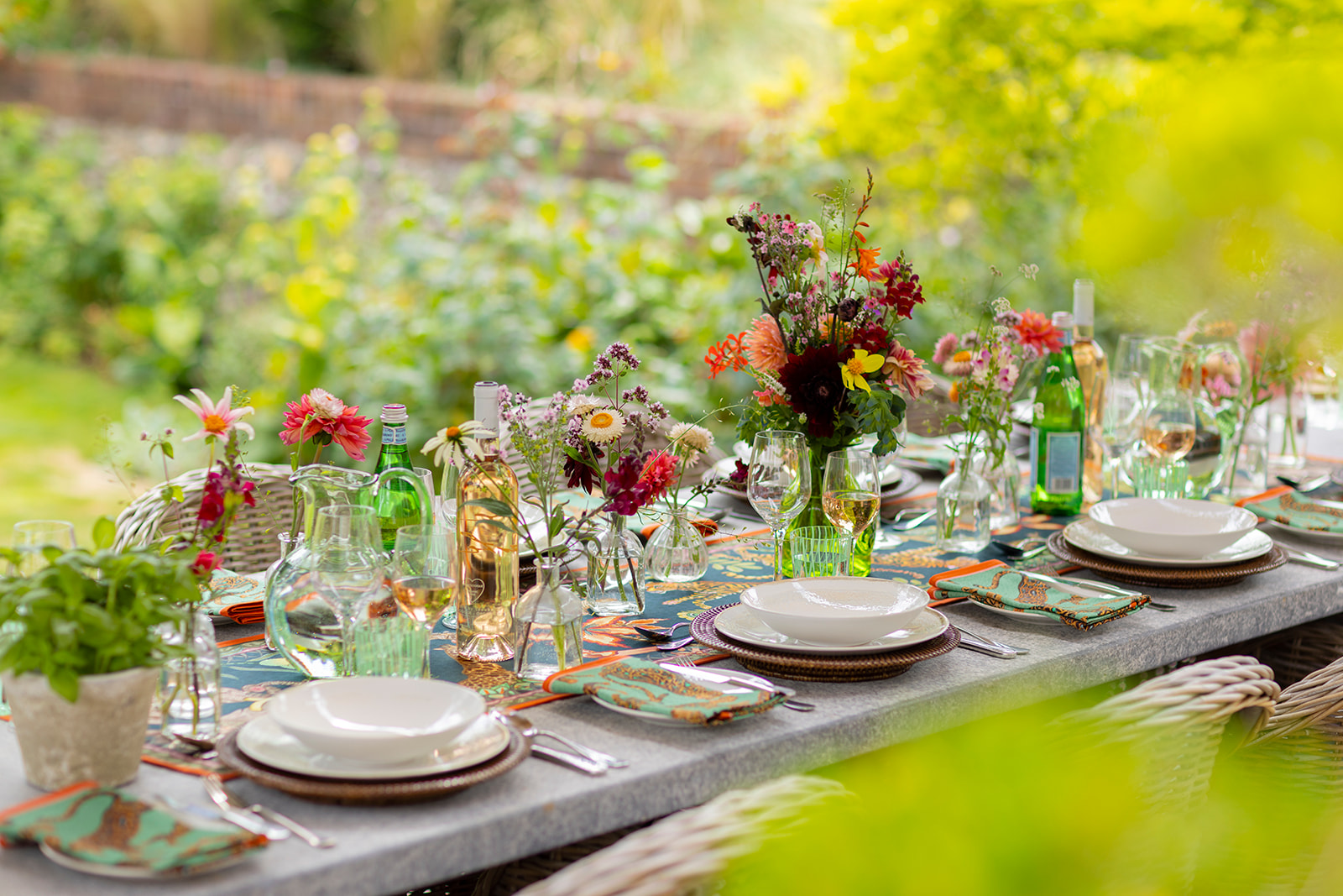 A decorated and laid outdoor dining table surrounded by woven chairs on a patio area