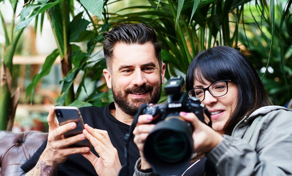 A man and woman smiling looking at a camera screen