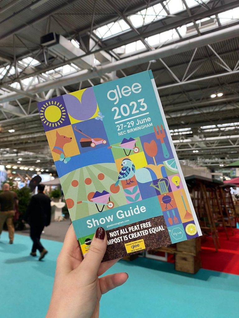 someone holding a brochure for 'glee 2023' in an event hall