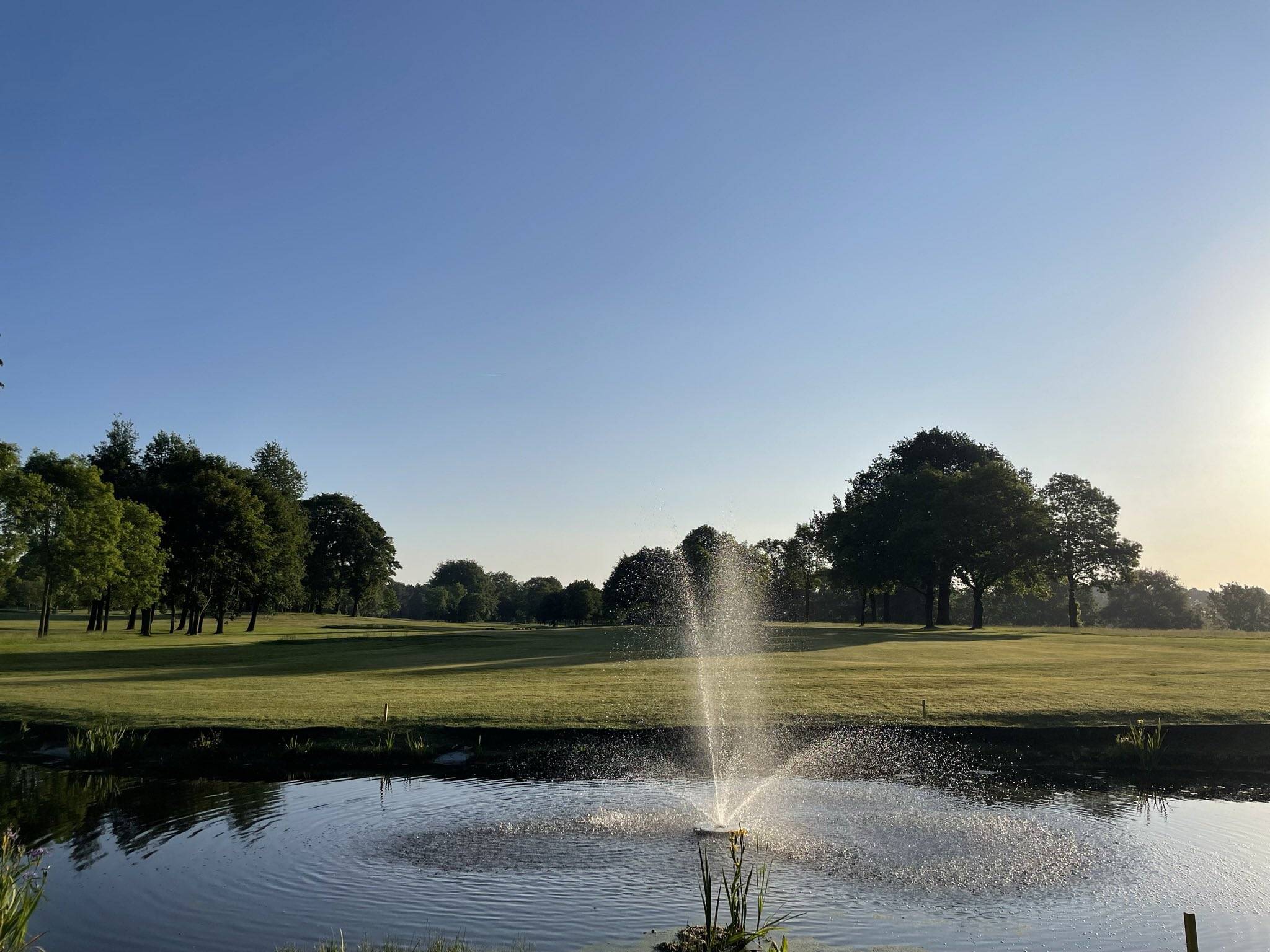 A large fountain in front of a large grassy area