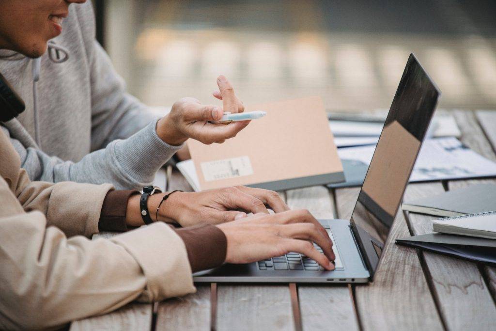 two people talking and using a laptop